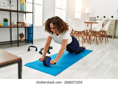 Mature Hispanic Woman Doing Exercise With Abdominal Wheel At The Living Room At Home