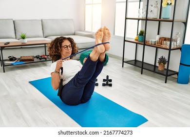 Mature Hispanic Woman Doing Exercise With Elastic Bands At The Living Room At Home