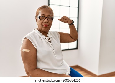 Mature Hispanic Woman Getting Vaccine Showing Arm With Band Aid Strong Person Showing Arm Muscle, Confident And Proud Of Power 