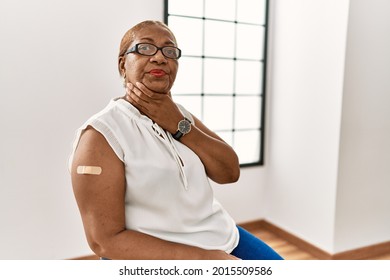 Mature Hispanic Woman Getting Vaccine Showing Arm With Band Aid Touching Painful Neck, Sore Throat For Flu, Clod And Infection 