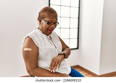 Mature Hispanic Woman Getting Vaccine Showing Arm With Band Aid Looking At The Watch Time Worried, Afraid Of Getting Late 