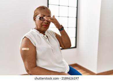 Mature Hispanic Woman Getting Vaccine Showing Arm With Band Aid Covering Eyes With Hand, Looking Serious And Sad. Sightless, Hiding And Rejection Concept 