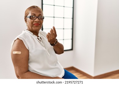 Mature Hispanic Woman Getting Vaccine Showing Arm With Band Aid Beckoning Come Here Gesture With Hand Inviting Welcoming Happy And Smiling 