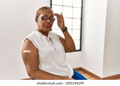 Mature Hispanic Woman Getting Vaccine Showing Arm With Band Aid Worried And Stressed About A Problem With Hand On Forehead, Nervous And Anxious For Crisis 