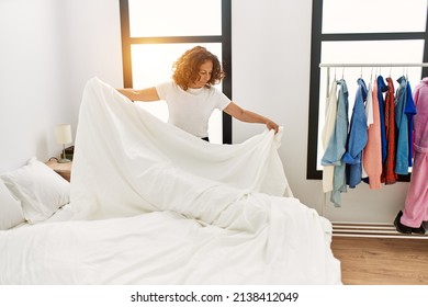Mature Hispanic Woman Making The Bed At The Bedroom