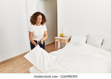 Mature Hispanic Woman Making The Bed At The Bedroom