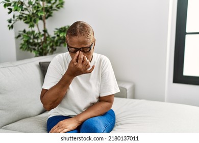 Mature hispanic woman sitting on the sofa at home tired rubbing nose and eyes feeling fatigue and headache. stress and frustration concept.  - Powered by Shutterstock