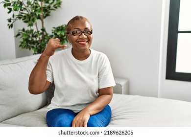 Mature Hispanic Woman Sitting On The Sofa At Home Smiling Doing Phone Gesture With Hand And Fingers Like Talking On The Telephone. Communicating Concepts. 