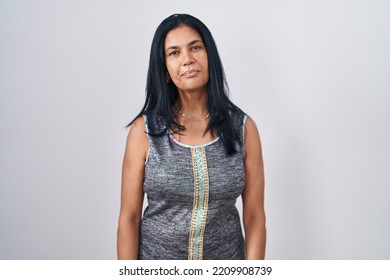 Mature Hispanic Woman Standing Over White Background Relaxed With Serious Expression On Face. Simple And Natural Looking At The Camera. 