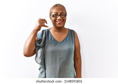 Mature Hispanic Woman Wearing Glasses Standing Over Isolated Background Smiling Doing Phone Gesture With Hand And Fingers Like Talking On The Telephone. Communicating Concepts. 