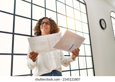 Mature Hispanic Woman Working Looking At Papers At The Office