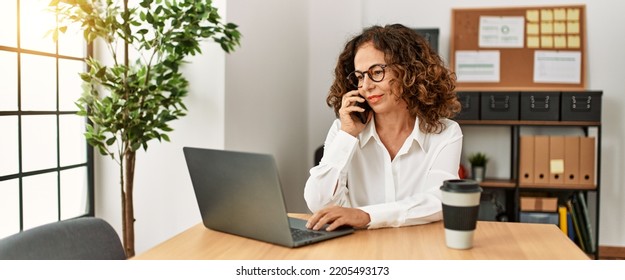 Mature Hispanic Woman Working Speaking On The Phone At The Office
