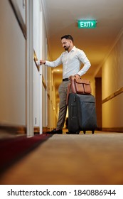 Mature Hotel Guest Opening With Luggage Opening Door Of His Room In Hotel