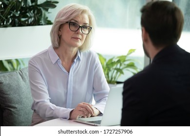 Mature hr manager listen applicant during job interview in office, looking at candidature with skepticism not sure that person is suitable for vacant position, client and bank worker meeting concept - Shutterstock ID 1727257906