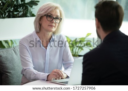 Mature hr manager listen applicant during job interview in office, looking at candidature with skepticism not sure that person is suitable for vacant position, client and bank worker meeting concept