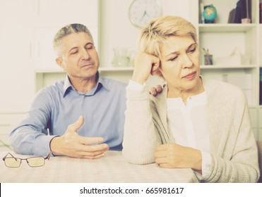 mature husband and wife arguing with each other and try to resolve family conflict at table - Powered by Shutterstock