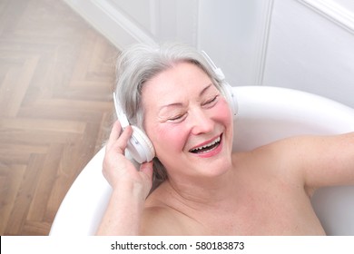 Mature lady entertaining herself with music while having a bath