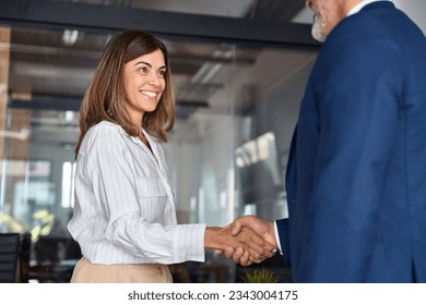 Mature Latin business team of woman and European business man shaking hands as colleagues, partners or employees, signing a contract. Group of people satisfied with results of team work together. - Powered by Shutterstock