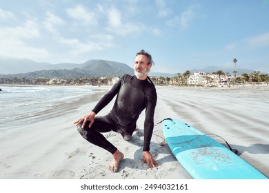 mature latin man surfer stretching on the beach before going in to surf the waves - Powered by Shutterstock