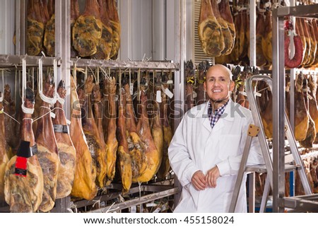 Mature Latina Butcher Hanging Wurst And Jamon Joints At Meat Factory Mature Latina Butcher Hanging Wurst And Jamon Joints At Meat Factory