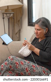 Mature Latina Woman Knits At Home, Learning Handicrafts Online.