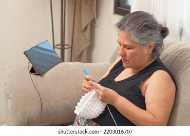 Mature Latina Woman Knits At Home, Learning Handicrafts Online.