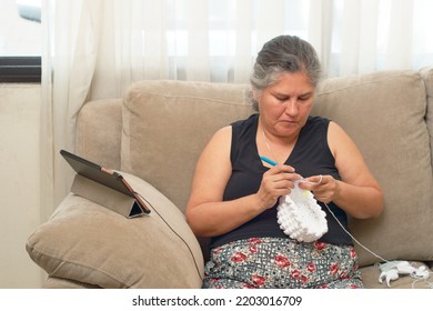 Mature Latina Woman Knits At Home, Learning Handicrafts Online.