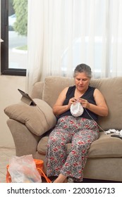 Mature Latina Woman Knits At Home, Learning Handicrafts Online.