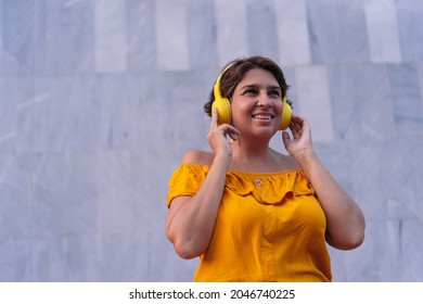 Mature Latina Woman Listening To Music With Headphones In The Street