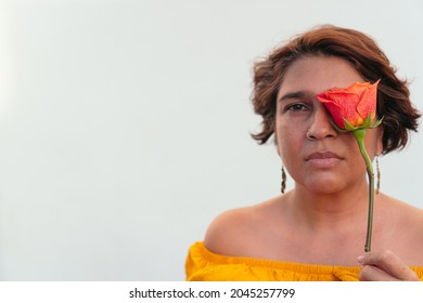 Mature Latina Woman With An Orange Flower Looking At The Camera