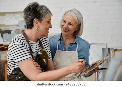 A mature lesbian couple in an art studio, painting together and sharing a happy moment. - Powered by Shutterstock