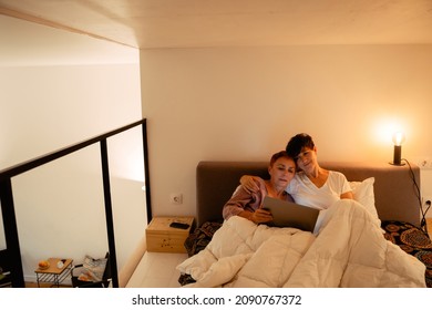 Mature Lesbian Couple Hugging And Using Laptop In Bed At Home