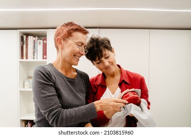 Mature Lesbian Couple Smiling While Cooking Together In Kitchen At Home