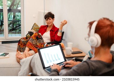 Mature Lesbian Couple Using Laptop And Reading Book At Home