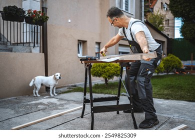 Mature male carpenter measuring wooden plank outdoors - Powered by Shutterstock