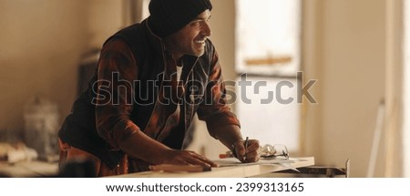 Mature male construction worker redesigns the interior of a house, focusing on the kitchen. He happily works on the renovation, using blueprints and a pencil to create an upgraded space.