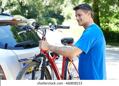 Mature Male Cyclist Taking Mountain Bike From Rack On Car