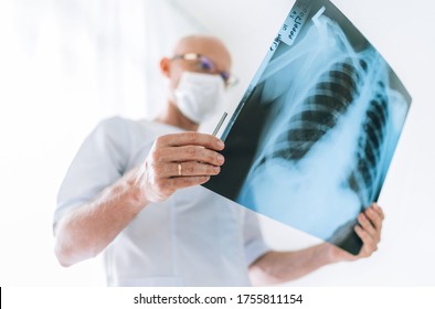 Mature Male Doctor Examining The Patient Chest X-ray Film Lungs Scan At Radiology Department In Hospital. Scan Close Up. Covid-19 Scan Body Xray Test Detection For Covid Worldwide Virus Spread Concept