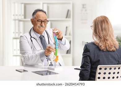 Mature male doctor showing a cervical spine model to a female patient at the office  - Powered by Shutterstock - Get 15% off with code: PIKWIZARD15
