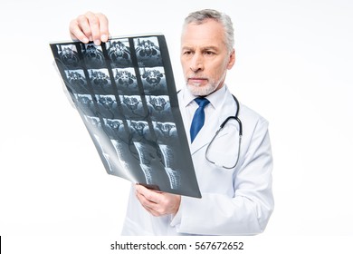 Mature male doctor with stethoscope looking at x-ray isolated on white - Shutterstock ID 567672652