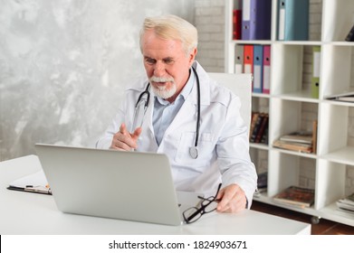 Mature Male Doctor Is Using Laptop For Consultation Online. Virtual Doctor Visit Concept