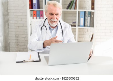 Mature Male Doctor Is Using Laptop For Consultation Online. Virtual Doctor Visit Concept