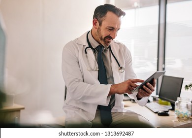 Mature Male Doctor Using Tablet Computer At His Office. General Practitioner Using Digital Tablet At His Clinic.