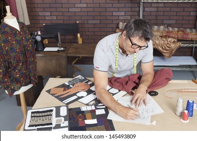 Mature Male Fashion Designer Working On Sketch In Design Studio