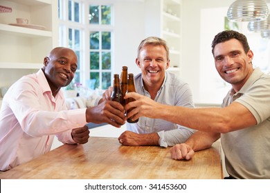 Mature Male Friends Sit At Table Drinking Beer And Talking