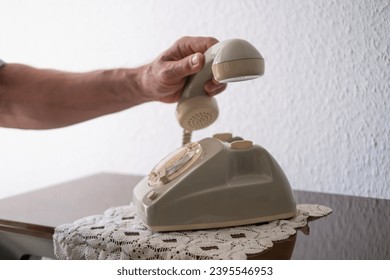 mature male hand removing Handset, rotating Dialer on Old white Rotary Telephone with Disc Dial, putting retro phone reciver down, Senior person with rotary phone, psychological support
