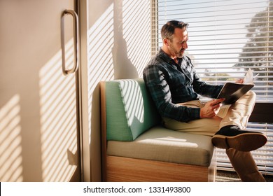 Mature male patient reading a book in the doctor's waiting room. Male patient at reception of clinic, sitting on sofa with a book.