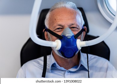 Mature male patient wearing oxygen mask during hyperbaric oxygen therapy and looking at camera.  - Powered by Shutterstock