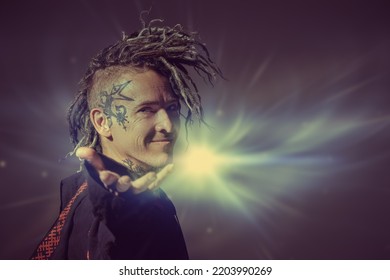 A mature male shaman in ethnic clothes stretches his hand forward with a smile, inviting you into his mysterious world. Dark background with mystical light. Halloween, Fantasy. Copy space. - Shutterstock ID 2203990269