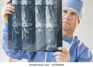 Mature male surgeon examining X-ray report in hospital